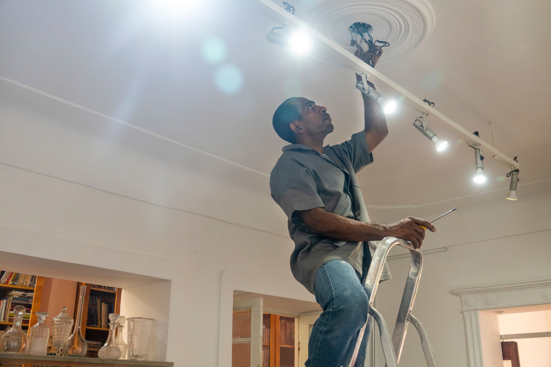 Electrician repairs the wiring of light bulbs in a room in the house